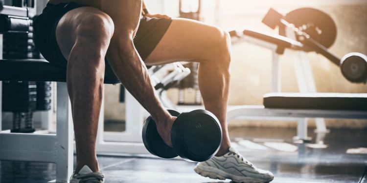 Uomo che solleva un peso in palestra, stimolando l'anabolismo muscolare attraverso l'allenamento di forza