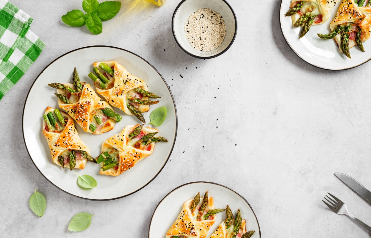 su sfondo bianco piatto con pasta fillo con asparagi. sulla destra ciotolina con salsa per degustare la ricetta