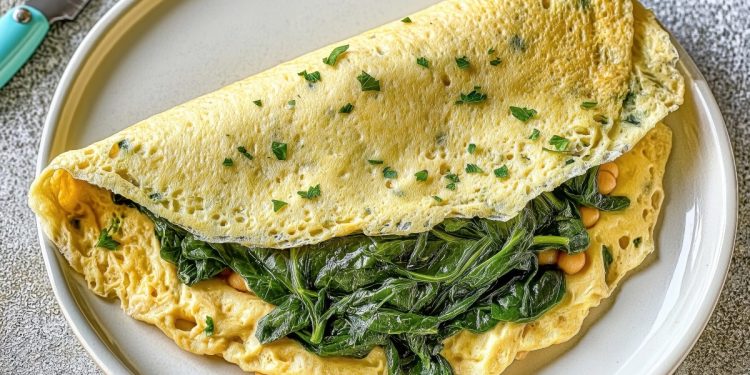 ricette con frittata: in primo piano, un piatto bianco con una frittata di albumi con la verdura dentro. Accanto un coltello azzurro