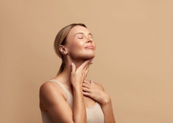 in primo piano una donna che massaggia il suo collo con un prodotto a base di peptidi per avere una pelle sempre giovane e radiosa