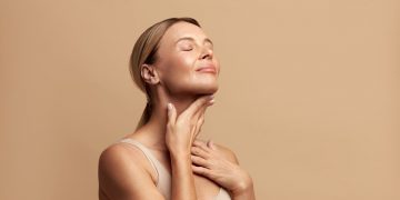 in primo piano una donna che massaggia il suo collo con un prodotto a base di peptidi per avere una pelle sempre giovane e radiosa