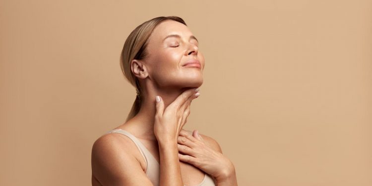 in primo piano una donna che massaggia il suo collo con un prodotto a base di peptidi per avere una pelle sempre giovane e radiosa