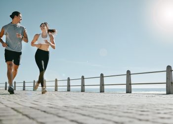 coppia che fa running sul lungomare e si guardano sorridendo