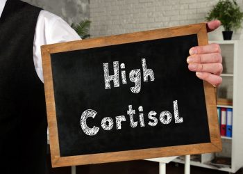 un uomo tiene in mano una lavagnetta con scritto high cortisol per indicare i sintomi del cortisolo alto