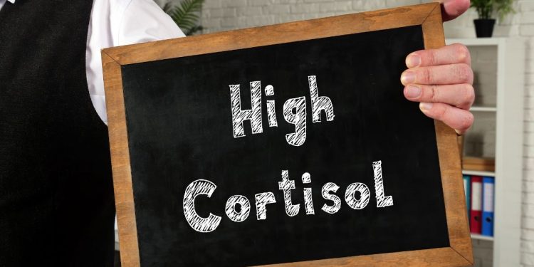 un uomo tiene in mano una lavagnetta con scritto high cortisol per indicare i sintomi del cortisolo alto