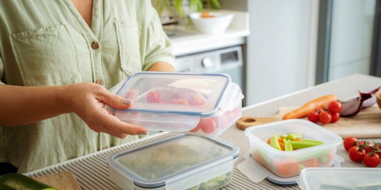 una donna che chiude dei contenitori alimentari per conservare il cibo