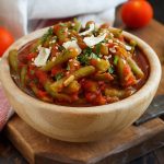 su tavolo, tagliere con ciotola in marmo con fagiolini all'uccelletto con alcuni fagiolini lavati e tagliati e dietro pomodorini