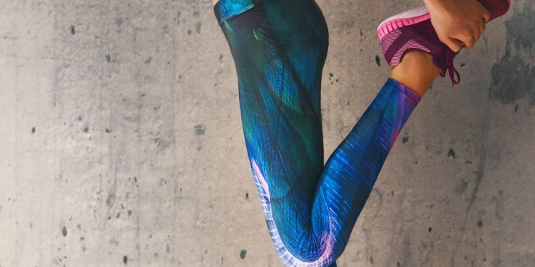 in primo piano una donna che indossa leggings sportivi con fantasie blu e scarpe da ginnastica viola