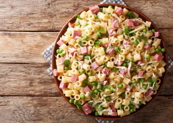 in primo piano un piatto di pasta con prosciutto cotto e piselli