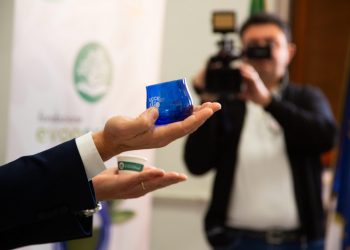 una mano in primo piano mostra un vasetto blu con il logo eccebio, un cameraman filma sullo sfondo