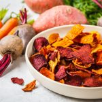su tavolo piatto con chips di carote e barbabietole con attorno carote e barbabietole
