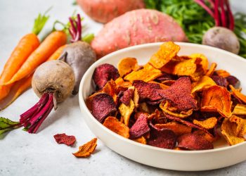 su tavolo piatto con chips di carote e barbabietole con attorno carote e barbabietole