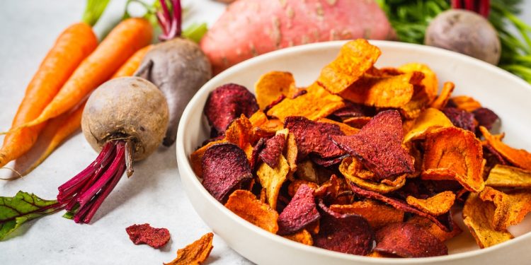 su tavolo piatto con chips di carote e barbabietole con attorno carote e barbabietole