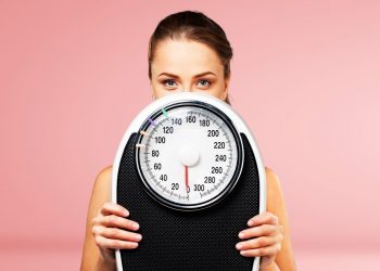 dieta 1500 calorie: una donna che tiene una bilancia in mano