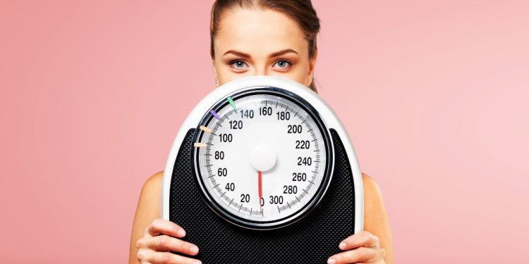 dieta 1500 calorie: una donna che tiene una bilancia in mano