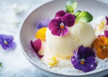 una pallina di gelato circondata da fiori commestibili