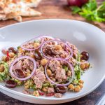 Insalata di ceci e tonno servita in un piatto fondo, con cipolla e olive taggiasche