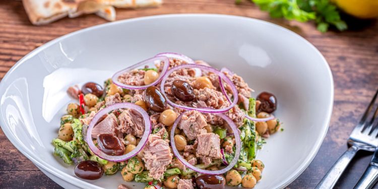 Insalata di ceci e tonno servita in un piatto fondo, con cipolla e olive taggiasche