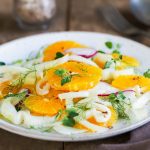 in primo piano su un piatto piano bianco una gustosa insalata di finocchi e arance, perfetta come contorno o antipasto