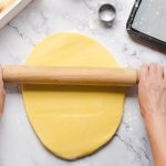 in primo piano la pasta frolla senza burro mentre viene stesa con un mattarello.