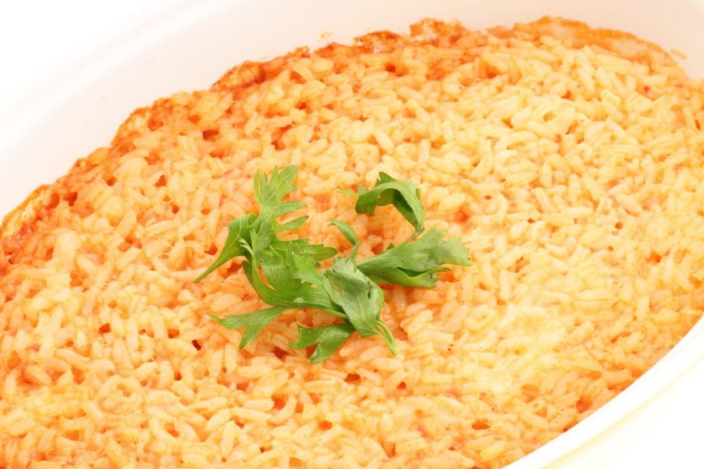 Riso al forno: il salva pasto comodo da preparare anche in anticipo 5 in primo piano in una pirofila di forma ovale del riso al forno guarnito con qualche foglia di basilico