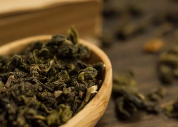 in primo piano, in una ciotola di legno delle foglie di tè oolong essiccate e arrotolate