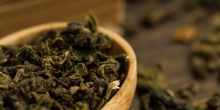in primo piano, in una ciotola di legno delle foglie di tè oolong essiccate e arrotolate
