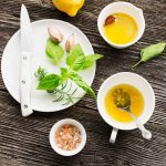 su tavolo di legno ingredienti per preparare la citronette: sale, limone, olio erbe aromatiche, sale e la ciotola piena di emulsione