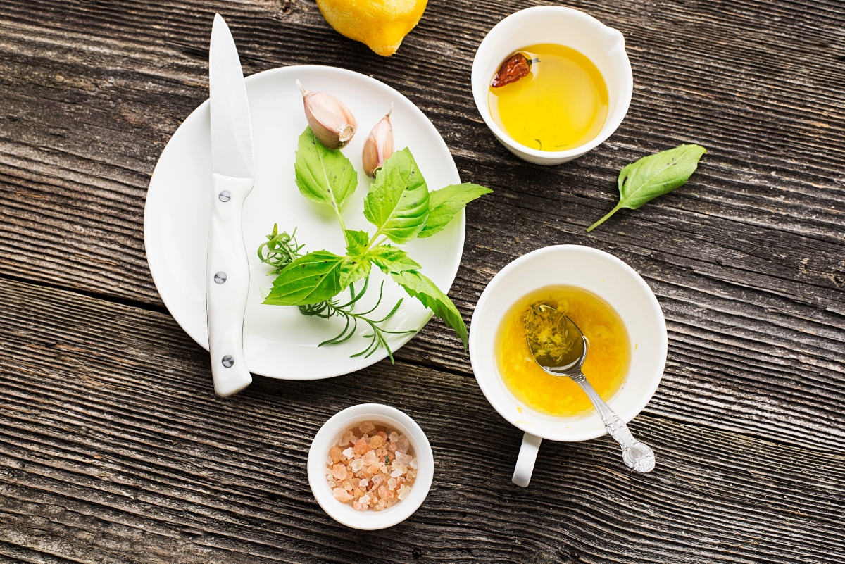 su tavolo di legno ingredienti per preparare la citronette: sale, limone, olio erbe aromatiche, sale e la ciotola piena di emulsione