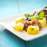 polpo con patate: su tavolo azzurro piatto bianco con insalata di polpo con patate