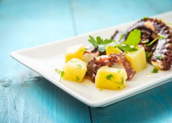 polpo con patate: su tavolo azzurro piatto bianco con insalata di polpo con patate