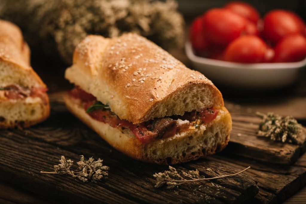 Pane cunzato: panino tipico siciliano, veloce da fare e ricco di gusto 3 in primo piano il pane cunzato siciliano condito con pomodori freschi, acciughe, origano e un filo d’olio extravergine