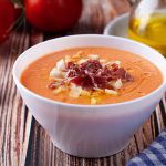 in primo piano dentro una ciotola bianca la zuppa fredda di salmorejo con uova sode e jamon serrano