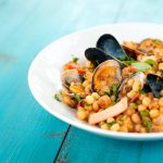 su tavolo di legno blu, un piatto bianco con la fregola ai frutti di mare