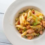 su base chiara una scodella bianca con della pasta zucchine e salmone