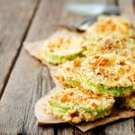 in primo piano delle schiacciatine di zucchine croccanti e dorate sopra un tavolo di legno