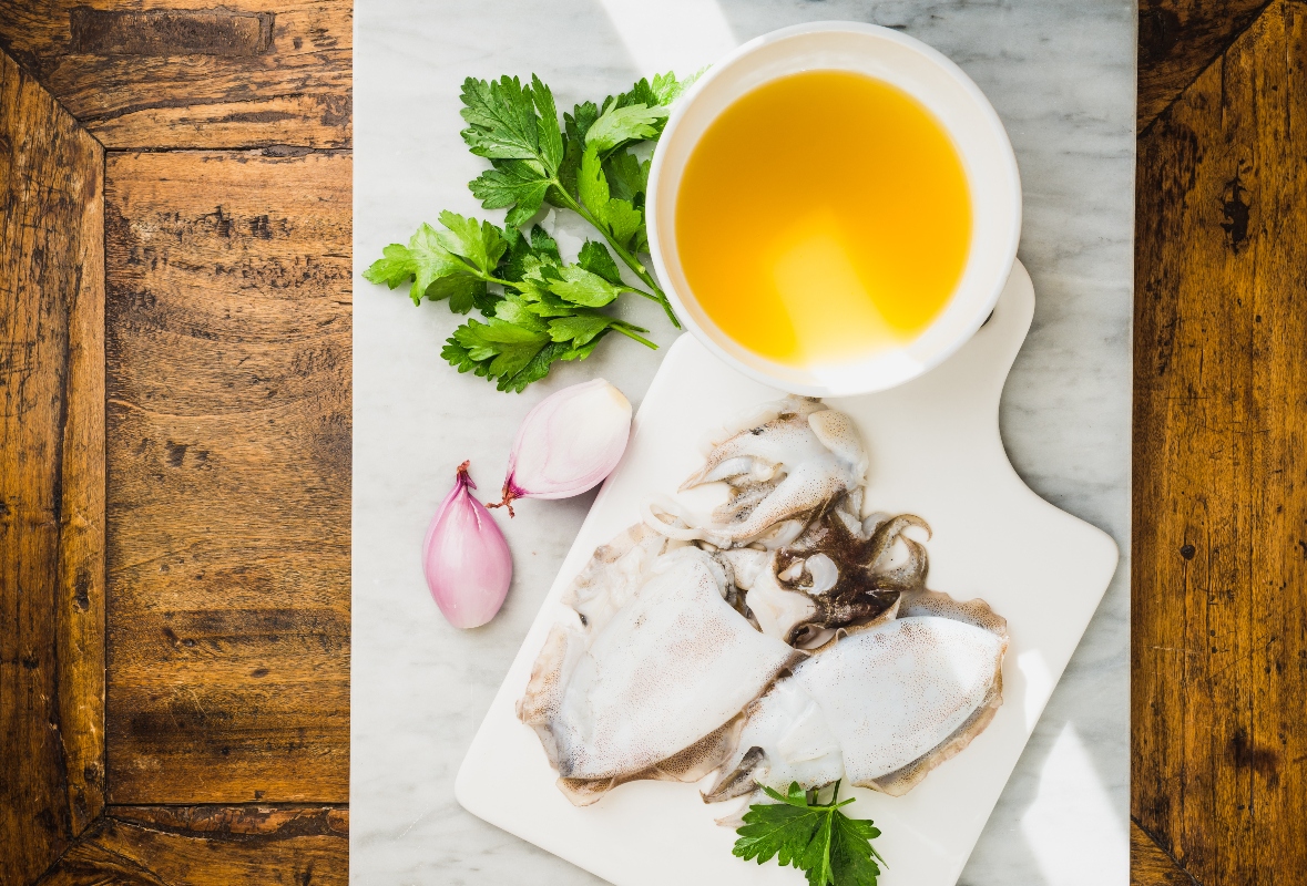 su tavolo di legno, tagliere di marmo con in una ciottola il fumetto di pesce, erbe aromatiche, cipolle e lische di pesce