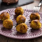 su tavolo di legno piatto viola e bianco con 7 polpette di cous cous
