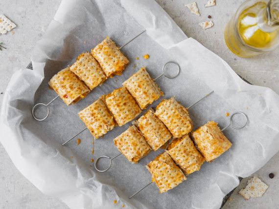 teglia rivestita di carta forno con dentro 4 spiedini di involtini di zucca