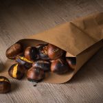 su tavolo di legno, un sacchetto di carta con castagne in friggitrice d'aria pronte ad essere mangiate