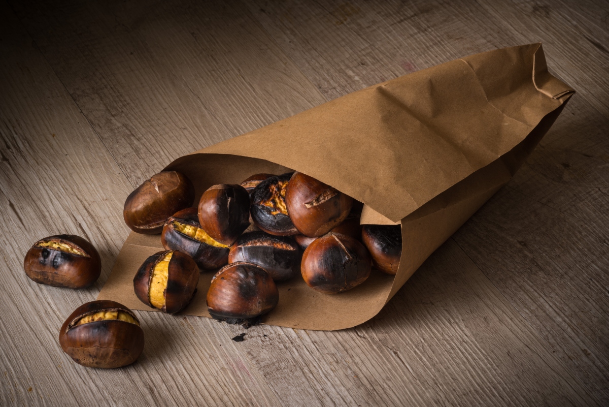 su tavolo di legno, un sacchetto di carta con castagne in friggitrice d'aria pronte ad essere mangiate