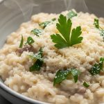 Riso in cagnone: ricetta e consigli di preparazione 1 primo piano di un piatto grigio con il riso in cagnone con burro e prezzemolo