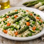 piatto piano bianco pieno di risotto primavera con verdure miste