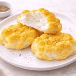 In primo piano su un tavolo chiaro ci sono delle uova alla jova soffici con una spolverata di pepe sopra.