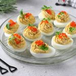 su tavolo bianco un piatto trasparente con le uova ripiene di tonno e uova di salmone