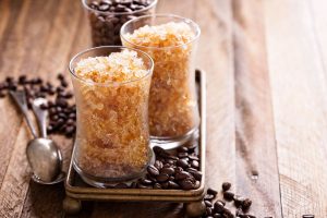 Iscriviti subito alla dieta Melarossa e scarica l'app 10 Due bicchieri di granita al caffè serviti su un vassoio con chicchi di caffè e un cucchiaino.