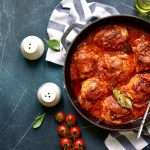 Pollo alla pizzaiola in padella: ricetta facile e leggera 1 su base grigio scuro una padella tonda con dentro pollo alla pizzaiola, saliere intorno