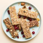 Barrette con cereali: uno snack facile e ricco di gusto 1 In primo piano su un piatto azzurro chiaro ci sono delle barrette ai cereali e frutta secca.