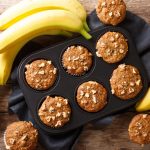 Muffin alla banana morbidi e profumati alla cannella 1 In primo piano su un tavolo di legno ci sono dei muffin alla banana.