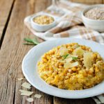 Orzotto: ricetta semplice e gustosa da fare in casa 1 Orzotto alla zucca con scaglie di Parmigiano e rosmarino servito in un piatto bianco.
